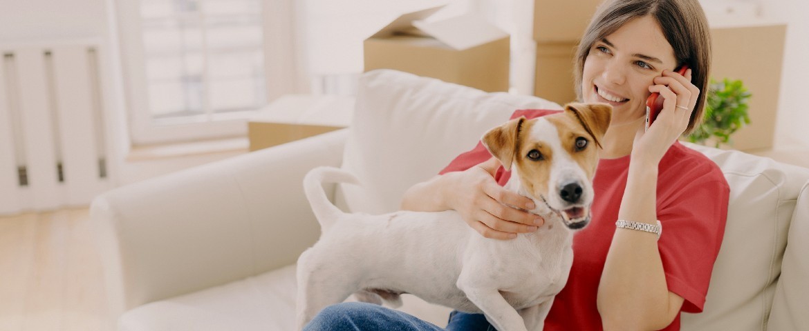 Une femme qui vient d'emménager, assise sur son canapé avec son chien
