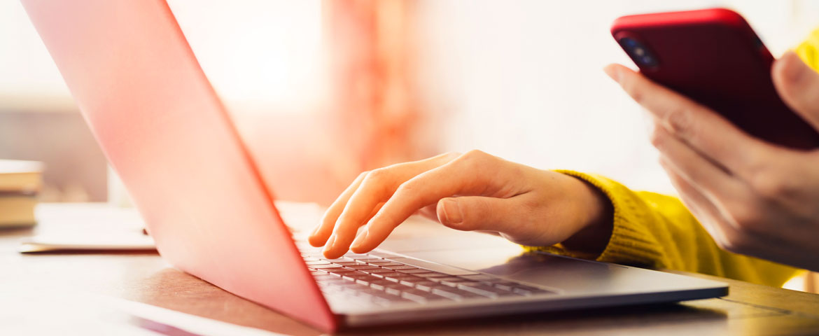 Une femme qui consulte son ordinateur avec son téléphone dans la main 