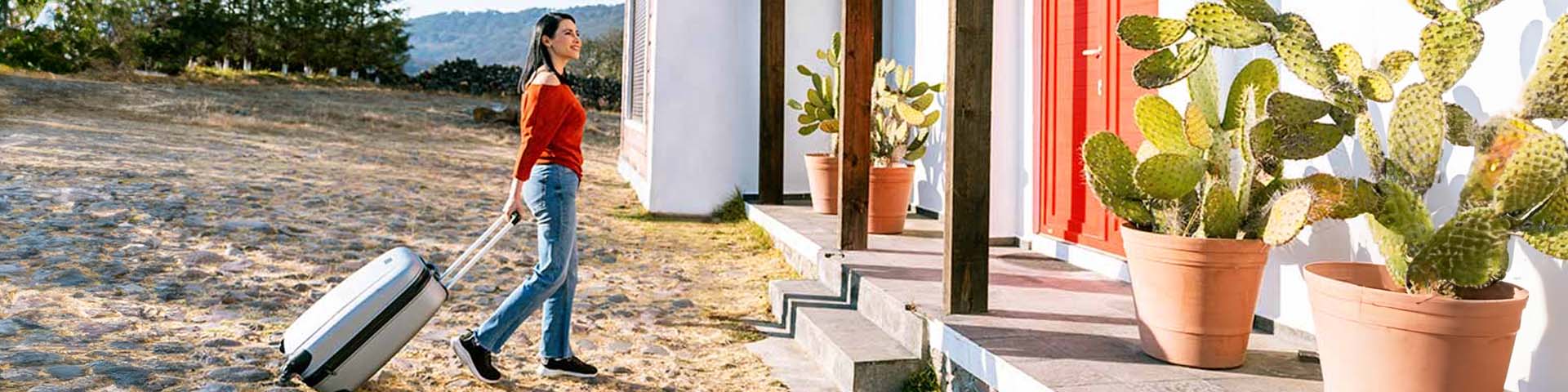 Une femme avec un valise devant une maison