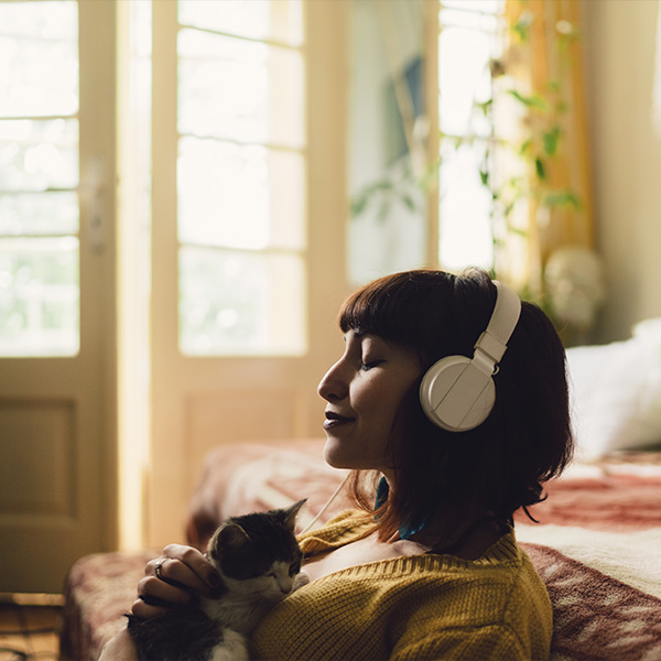 une femme qui écoute de la musique dans son salon avec un chat
