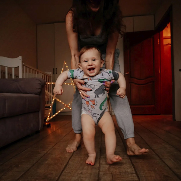 un bébé qui commence à marcher dans sa maison avec l'aide de sa maman