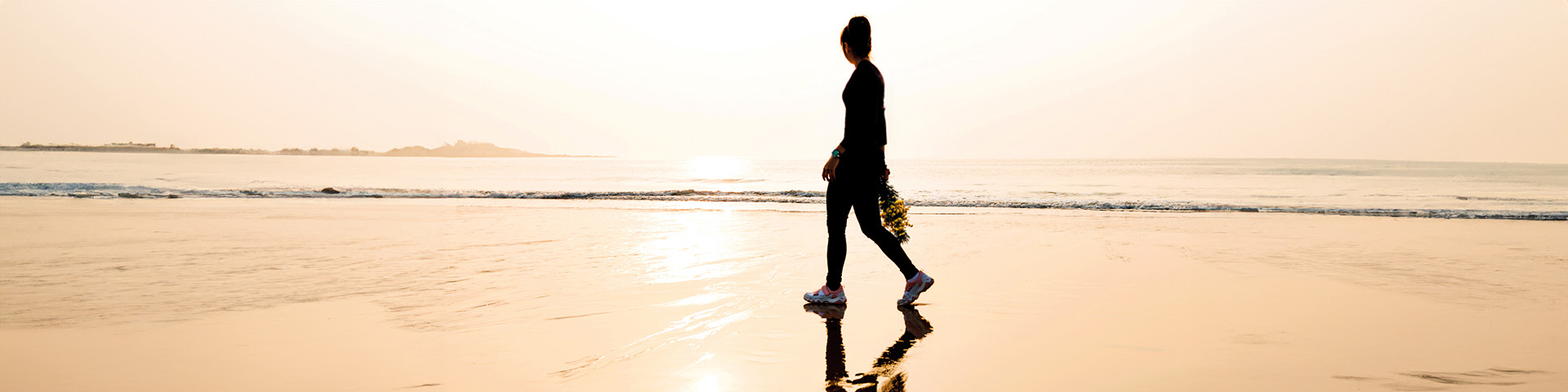 Silhouette d'une femme marchant sur le sable en bord de mer