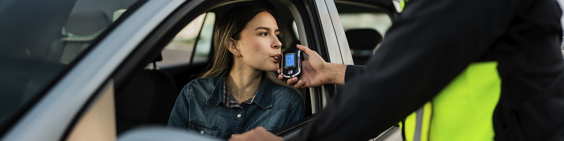 une femme au volant souffle dans un éthylotest