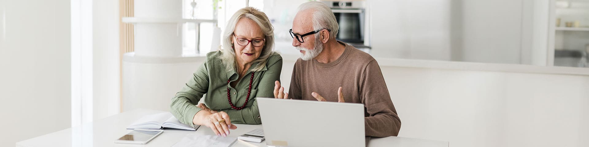 couple de seniors assis face à un ordinateur
