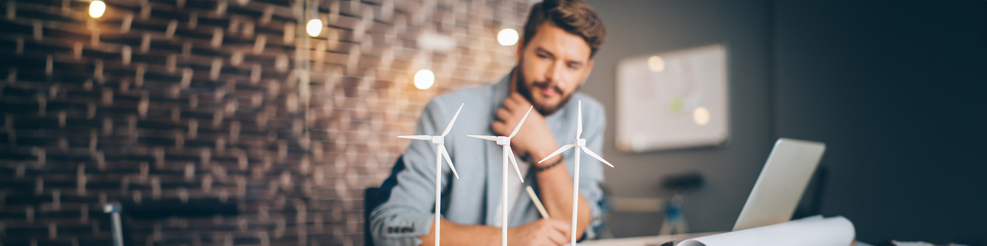 homme face des miniatures d'éoliennes posées sur son bureau
