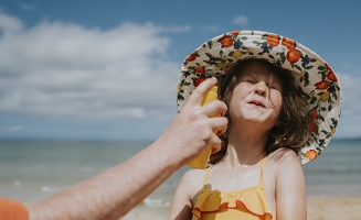 une jeune fille qui se fait mettre de la crème solaire