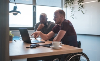 Deux homme au travail qui discutent, l'un est en fauteuil roulant
