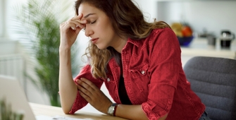 Une femme se tenant la tête sur son bureau