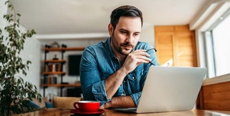 Un homme à son bureau qui consulte son ordinateur