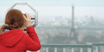 Une femme qui regarde la Tour Eiffel à l'aide de jumelles d'observations