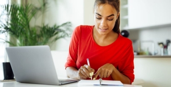 Un dame devant son ordinateur qui prend des notes