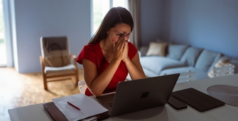 Une femme assise à sa table à manger consultant son ordinateur