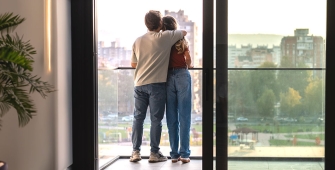 Couple qui s'enlace devant une fenêtre
