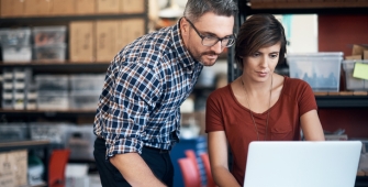 Une femme et homme regardant le même ordinateur dans un bureau