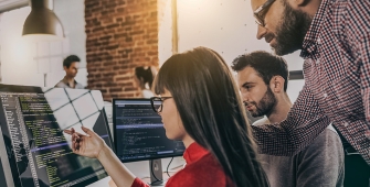 Plusieurs personnes regardant le même ordinateur dans un open space