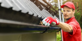 un homme qui nettoie une rigole de toit