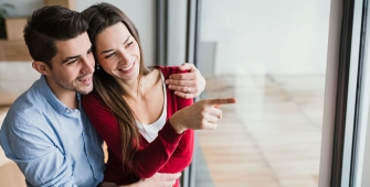 Un couple qui regarde par la fenêtre d'une maison