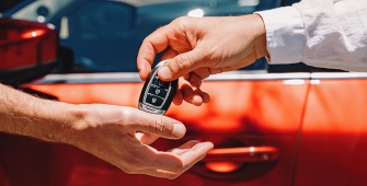 Une main qui tend une clé de voiture à une autre main