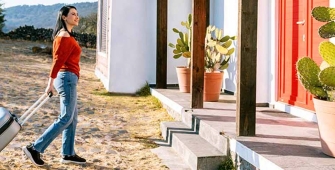 Une femme avec un valise devant une maison