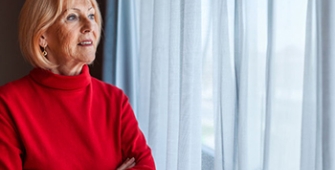 femme senior regardant par la fenêtre