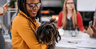 Une femme avec son chien dans les bras au travail