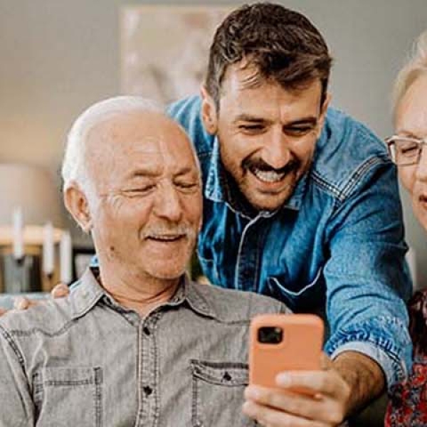 Un homme qui montre quelque chose sur son téléphone à ses parents
