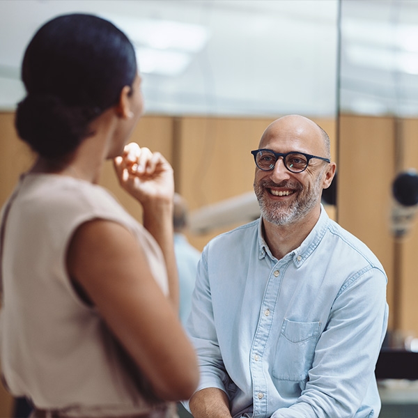 deux collègues dont un homme souriant et une femme de dos