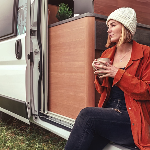 Une femme assise qui boit du thé dans son camping-car
