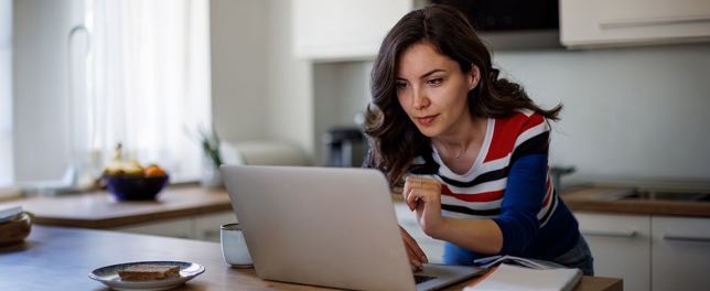 Une femme dans sa cuisine qui consulte son ordinateur 