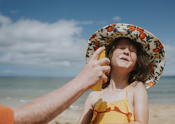 une jeune fille qui se fait mettre de la crème solaire