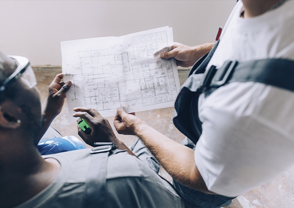 deux hommes regardant un plan de chantier