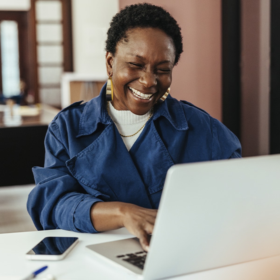 une femme qui sourit devant son ordinateur